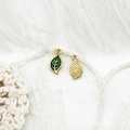 Macro view of detailed leaf-shaped jewelry pendants with green enamel and gold finish - Leaf