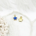 Macro shot of 18K gold plated blue star charms with smiling faces on lace background - Star