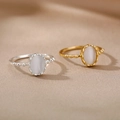 Detail of gold and silver beaded oval opal rings on elegant champagne silk fabric - Gold / Milky White Artificial Cat Eye Stone