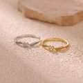 Detailed close-up of gold and silver wave rings with double zircon stones on beige stone - Wave Double Stone Style (JZ8269) / Gold