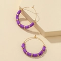 Detail of bohemian gold hoop earrings with purple heishi beads on a stone display - Purple