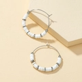 Detailed macro view of bohemian white heishi beads and silver metal beads on hoop earrings - White