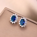Primer plano de aretes de girasol con piedra azul ovalada y circonitas blancas - Azul