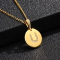 Detalle de un colgante de disco dorado con la letra U de circonita cúbica y cadena fina - Letra U