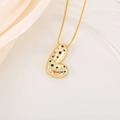 Gros plan du collier pendentif doré orné de zircons colorés sur plateau en satin blanc - L