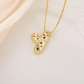 Vue macro du pendentif lettre Y doré avec zircons colorés sur un fond en soie douce - Lettre Y