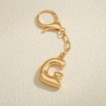 Dettaglio macro del portachiavi lettera G placcato oro 18K con finitura in metallo lucido - Lettera G