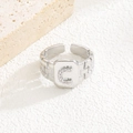 Detail eines silbernen geometrischen quadratischen Rings mit Zirkon-Buchstabe C und offenem Band - Buchstabe C Stil