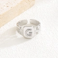 Makro-Detail des silbernen verstellbaren Rings mit Zirkonia-G-Buchstaben und Kettenstruktur - Buchstabe G Stil