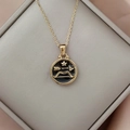 Close-up of golden zodiac pendant with black enamel and star bow design in a gift box - Gold-Sagittarius