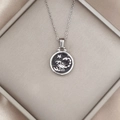 Detailed view of silver Scorpio zodiac pendant with black enamel on silk fabric - Silver-Scorpio
