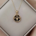 Detail of Aries zodiac pendant in gold finish with black enamel inlay on silk - Gold-Aries