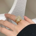 Dettaglio di un anello a quadrifoglio in oro con zirconi indossato su maglia nera - Stile Quadrifoglio Rotante (JZ-058J) / Oro