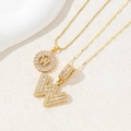 Detailed macro view of two gold letter W pendants with pavé-set cubic zirconia crystals - Letter W