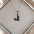 Macro view of a black enamel heart pendant necklace on silk in a jewelry box - Silver Black
