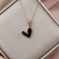 Close-up of black heart pendant with gold edge on silk fabric inside a jewelry box - Gold Black
