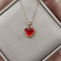 Detailaufnahme eines roten Herzanhängers an einer Goldkette auf einer Schmuckbox - Dunkelrot