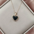 Detailed close-up of a 18K gold-plated heart pendant with black enamel on a silk background - Dark Gray