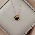 Detaillierte Makroansicht einer goldenen Kette mit schwarzem Ruyi-Anhänger in Geschenkbox - Silbergrau