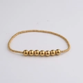 Detailaufnahme eines goldenen Perlenarmbands mit sieben polierten Spiegelglanz-Mittelperlen - Große Kernperle Gold Stil (BC596-4)