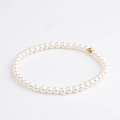Elegantes Armband aus weißen Perlen mit zentraler Goldperle auf neutralem Grund - Einzelne Goldperle Perle Stil (BC596-9)