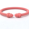 Macro shot of coral pink twisted cable cuff bracelet with matte finish and rounded ends - Pink