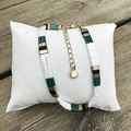 Detail of multi-layer Tila bead bracelet with gold lobster clasp and round metal charm - Green Color-Blocked Tila Bead Bracelet