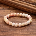 Détail d'un bracelet en perles dégradé rose et blanc sur une table en bois - Rose et Pêche (GBC024-9)