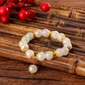 Iridescent beaded bracelet with golden floral spacers on a bamboo background - Milky White (GBC07-4)