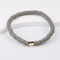 Detailed macro view of grey Heishi clay beads bracelet with a gold heart charm - Gray