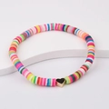 Nahaufnahme eines böhmischen Heishi-Perlenarmbands mit goldenem Herzanhänger - bunt