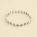 Pulsera vintage con eslabones blancos en X y cuentas doradas sobre fondo amarillo suave - Blanco