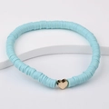 Close-up of light blue Heishi clay bead bracelet with a gold heart charm on a white stand - Light Blue