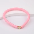 Detailed view of pink Heishi clay beads bracelet with a golden heart charm on white stand - Pink