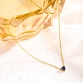Détail d'un collier doré avec pendentif coeur bleu en pierre de naissance sur fond texturé - Février Bleu Foncé