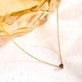 Close-up of a gold O-chain necklace with a purple heart-shaped gemstone on pink texture - June Purple