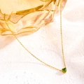 Detail of a gold stainless steel necklace featuring a vibrant green heart birthstone pendant - August Tender Green
