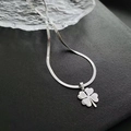 Détail macro du pendentif trèfle argenté sur une chaîne serpent en acier poli - Collier Motif Trèfle à Quatre Feuilles (8828) / Argent