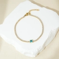 Dettaglio di un bracciale tennis dorato con piccoli cristalli e pietra blu quadrata - Oro 18K / Placcato Oro Zirconia Blu