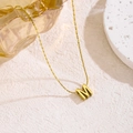 Elegante goldene Edelstahlkette mit 3D-Buchstaben-M-Anhänger auf strukturierter Fläche - Buchstabe M