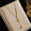 Collier en acier titane doré avec pendentif lettre A et pompon cube sur boîte à bijoux - Lettre A