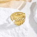 Detalle del anillo de hoja de palma dorada sobre piedra, diseño calado y elegante - Trigo Doble Dorado