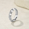 Vue macro d'une bague en titane argenté sertie de zircons ronds de forme carrée - Taille 6 / Acier