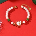 Detalle de pulsera navideña con colgante de Papá Noel y perlas en un fondo rojo festivo - Estilo Papá Noel (SL8981)