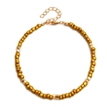 Detail of gold beaded anklet featuring square alloy spacers and secure lobster clasp - Yellow