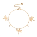 Golden dragonfly anklet with hollow charms, rhinestones and a bell on white background - Gold