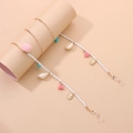 Dettaglio catena per occhiali con nappe colorate, pompon rosa e ciondoli a conchiglia - Oro