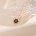Detailed macro view of heart pendant with purple gemstone on gold chain necklace - Violet