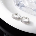 Close-up of silver huggie earrings featuring triple rows of sparkling cubic zirconia - Silver
