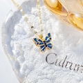 Close-up of butterfly necklace with blue rectangle stones on a glass tray - Hollow Butterfly Necklace / Medium Blue